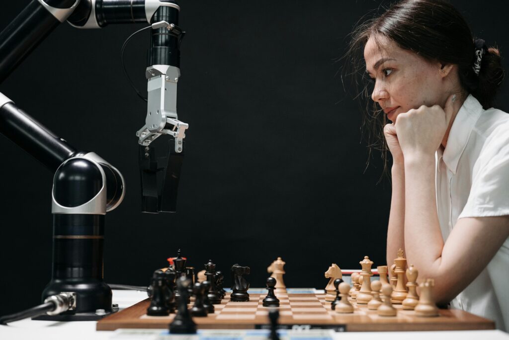 A focused woman playing chess with a robotic arm